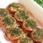 Baked Provençal tomatoes in a white dish, topped with garlic, herbs, and olive oil, slightly roasted and juicy
