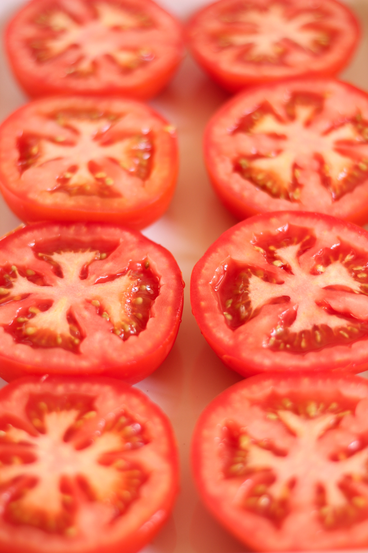 Raw tomatoes cut in half in a baking dish.