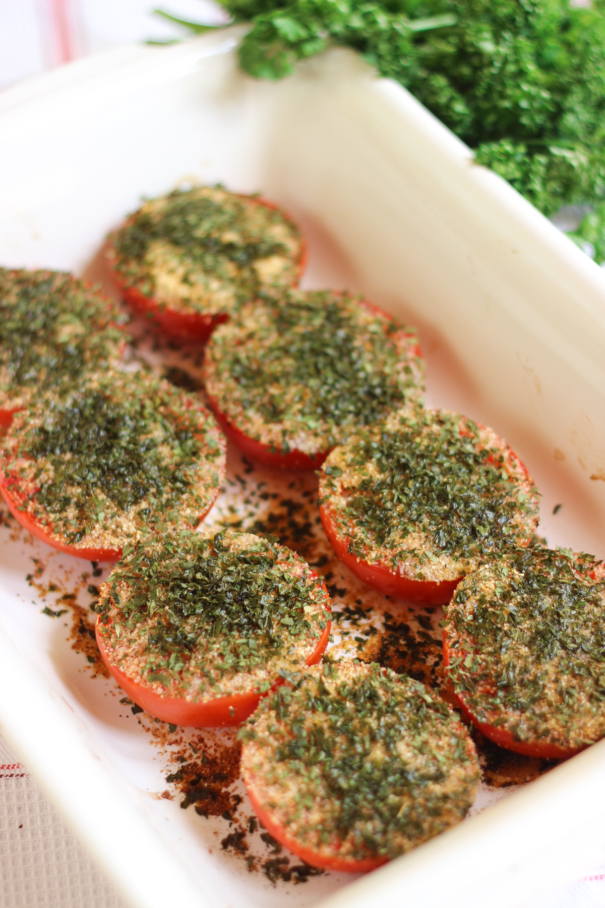 Baked Provençal tomatoes in a white dish, topped with garlic, herbs, and olive oil, slightly roasted and juicy