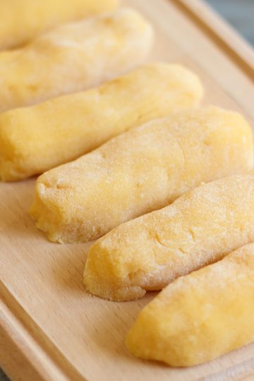 Homemade quenelles shaped and ready to cook on a wooden board